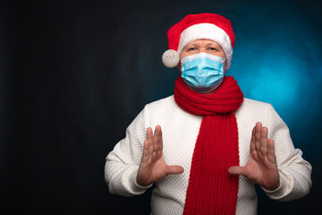 Fototapeta na wymiar European man wearing a medical mask and a red Christmas hat on a black background. Pandemic coronavirus, quarantine, 2020, 2021. Celebrating the New Year, stay at home, covid-19, holiday, isolation
