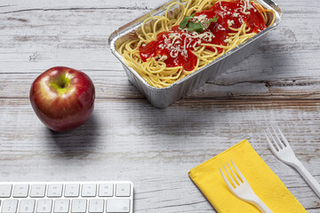 Lunch at workplace spaghetti with tomato and cheese on work table