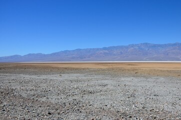View from highway 190 towards salt flats of Badwater Basin, Death Valley, California, blue sky background