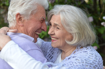 Beautiful senior couple hugging by lilacs in the park