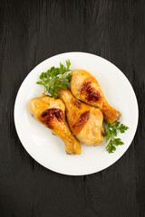 Top view of fried chicken legs in the white plate on the black background. Location verical.
