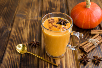 Smoothies with pumpkin and cinnamon in the glass cup on the wooden  background