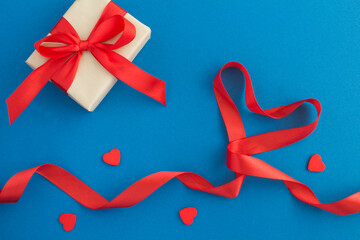 Red heart shaped ribbon and gift on the blue  background