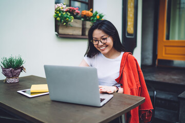 Cheerful Asian woman working on laptop