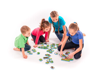 Kids of different age solving jigsaw puzzle together