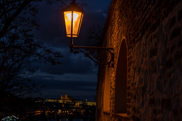 
light from street lights and the old stone walls of the fortress from the 15th century and paving stones on the ground for pedestrians at night in the center of Prague in the Czech Republic in autumn