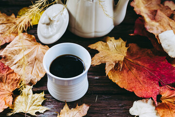 Tasse de café expresso en grès blanc et arrière plan avec des feuilles d'automne et un bouquet...
