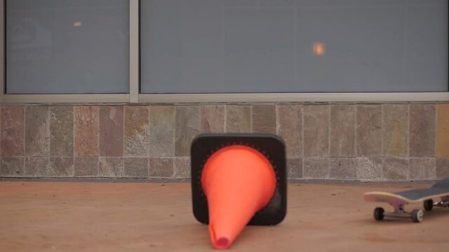 Failing during skateboard jump trick. Brick wall and skateboarder fails during his jump over the orange road conus.