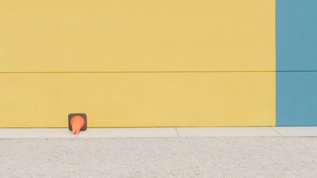 Yellow background and young man jumps over the conus. Man performs skateboard jump.