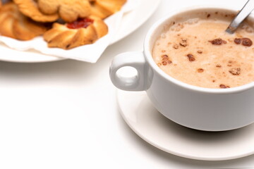 Cup of cocoa with lumps with pastries on white background