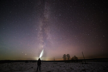 silhouette of a man with a flashlight on the background of a clear sky and a beautiful milky way