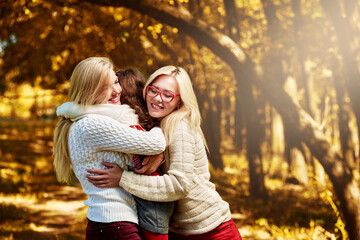 Fototapeta premium Three happy lovely sisters hugging in autumn park