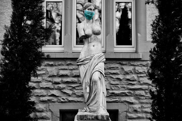 Black and white photograph of a statue with a face mask duric the pandemic of 2020