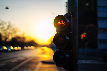 Photograph of a traffic light for bicycles in the evening with the setting sun in the background