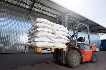 Red forklift lifts pallet with heavy bags