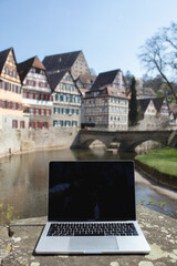 A laptop standing in the middle of a city and symbolizing barrier-free working. It also shows that...