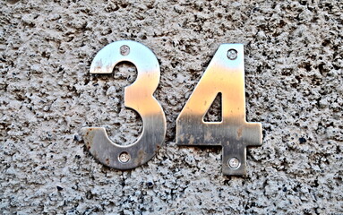 Number 34, thirty-four, metal numbers of a rough wall.