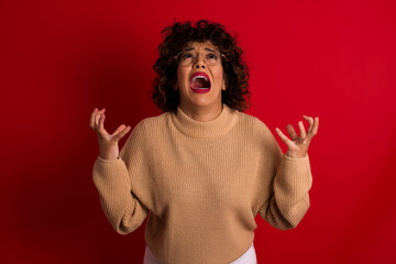 Young beautiful Arab woman wearing beige sweater against red background crying and screaming. Human...