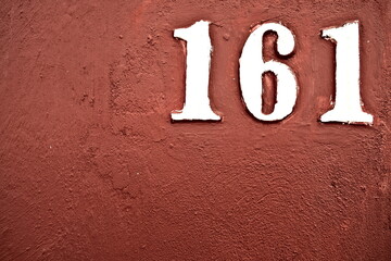Number 161, one hundred and sixty one, in white digits on brown background, offset in corner.