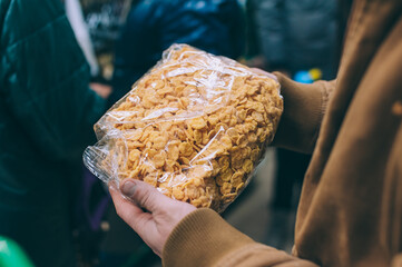 A man in a supermarket holds a bag of cereals.