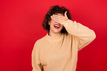 Happy MODEL closing eyes with hand going to see surprise prepared by friend standing and smiling in anticipation for something wonderful.