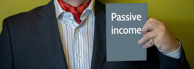 A man in a suit holds a sign with the text PASSIVE INCOME in his hands.