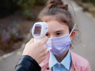 High body temperature. Close-up of a hand scans a child with a digital thermometer and measures...