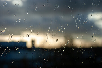 Raindrops on the glass of a window, blurred cloudy sky in the background