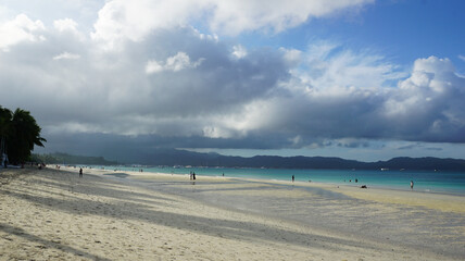 sunrise with shadows from clouds on white beach of boracay in philippines, tranquil tropical morning, traveling concept