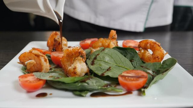 Mediterranean cuisine. chef pours sauce over vegetarian seafood salad with shrimps. finishing salad for guest of restaurant. Tasty and delicious fine dish, Slow motion. Full hd