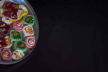 Oriental sweets in a round metal tray on a dark background
