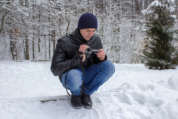 man shoots on camcorder in winter,videographer shoots nature in the park in winter in the snow
