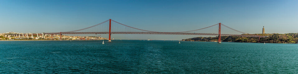 Fototapeta premium A panorama view of the suspension bridge over the Tagus river, Lisbon, Portugal named after the 25th April revolution viewed from the river