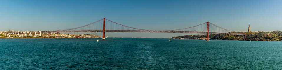 A panorama view of the suspension bridge over the Tagus river, Lisbon, Portugal named after the 25th April revolution viewed from the river