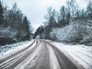 snowy road surrounded by pine trees, driving in winter snow on a country road, selective focus and motion effect