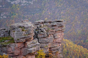 Impressive, red, rocky peak Tumba in front of autumn colored forest trees on the hills in the background