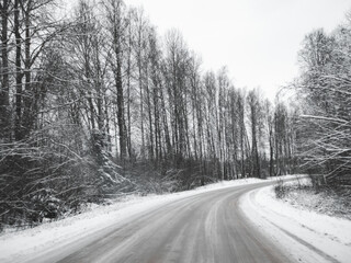 snowy road surrounded by pine trees, driving in winter snow on a country road, selective focus and motion effect