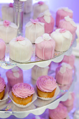 Cupcakes and other cakes with icing on glowing paper on plate
