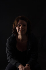 Fototapeta premium portrait of a woman sitting on black background