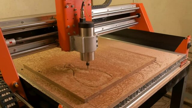 The cnc machine pulls out a wooden cutting board from a blank fixed to the table. Engraving and carpenter work