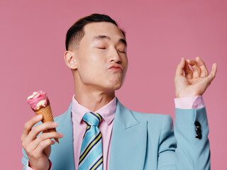 Emotional man in suit with ice cream in hands enjoying pink background