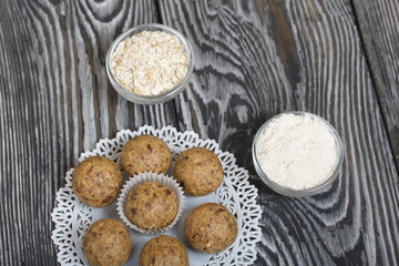 Dried fruit and oatmeal sweets. Nearby ingredients for their preparation. On black pine boards.