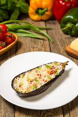 Eggplant stuffed with vegetables baked with parmesan and ingredients on a rustic wooden table. Close up. Selected focus.