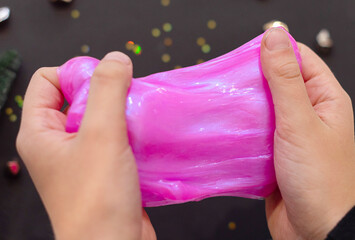 Kid playing with slime, child making slime on black Christmas background