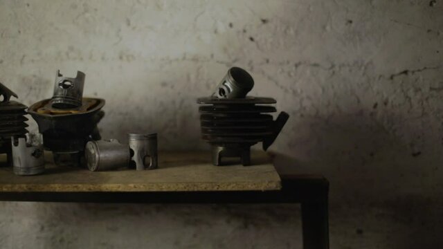 Shelf with spare parts in the garage. 
A man's hand puts a piston on the shelf and takes a new one. Motorcycle parts