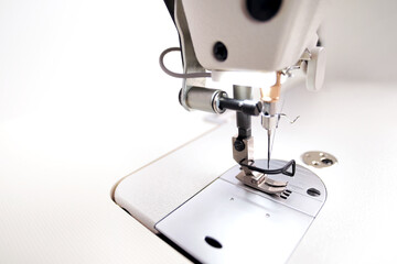 side of the machine head of a modern industrial sewing machine equipped with a narrow sewing foot for highspeed production of clothing - background blanked out blurry