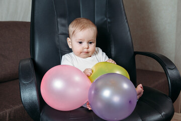 baby playing in a chair with colorful balloons