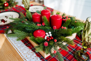 red color in the design of the new year's table, on the table is a Christmas tree candles plates tablecloth, table setting for the holiday, new year's table