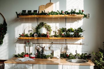 the kitchen is decorated with fir branches garland and toys, Christmas interior decor, cozy space for cooking, kitchen area