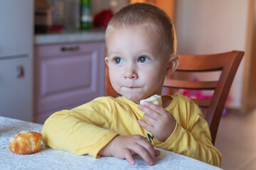 A little boy sits at a table and eats